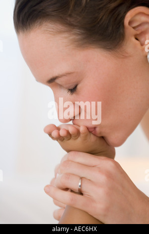 Hispanische Mutter Babys Fuß küssen Stockfoto