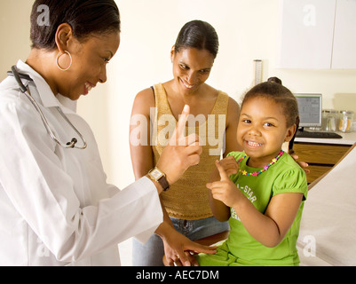 Afrikanische amerikanischer Arzt untersucht kleine Mädchen mit Mama im Zimmer. Stockfoto