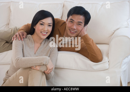 Asian paar lächelnd auf sofa Stockfoto