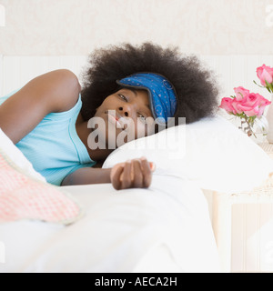Afrikanerin Augenmaske im Bett tragen Stockfoto