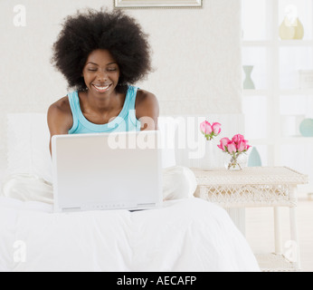 Afrikanische Frau mit Laptop am Bett Stockfoto