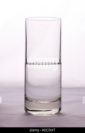 Ein Glas, das halb voll oder halb leer ist, um die Idee von Pessimismus oder Optimismus auf einem einfachen Hintergrund zu veranschaulichen Stockfoto