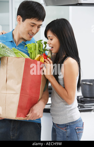 Asiatische paar auf der Suche in Einkaufstüte in Küche Stockfoto