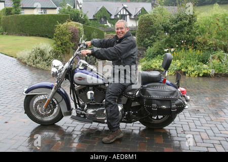 60 Jahre alten Mann mit Harley-Davidson Motorrad außerhalb seines Hauses Leute Lifestyle Wales Stockfoto