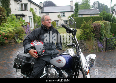 60 Jahre alten Mann mit Harley-Davidson Motorrad außerhalb seines Hauses Leute Lifestyle Wales Stockfoto