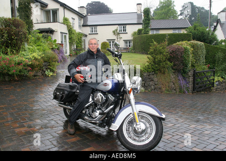 60 Jahre alten Mann mit Harley-Davidson Motorrad außerhalb seines Hauses Leute Lifestyle Wales Stockfoto