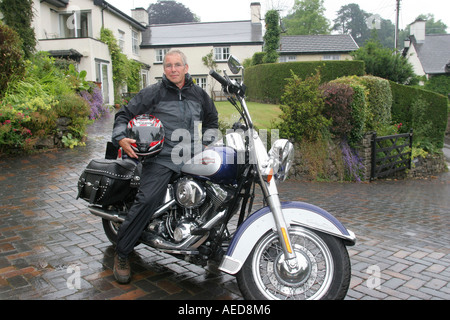 60 Jahre alten Mann mit Harley-Davidson Motorrad außerhalb seines Hauses Leute Lifestyle Wales Stockfoto