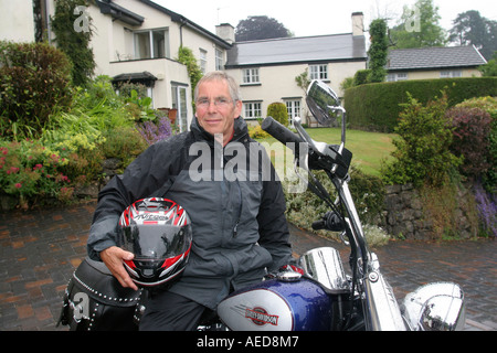 60 Jahre alten Mann mit Harley-Davidson Motorrad außerhalb seines Hauses Leute Lifestyle Wales Stockfoto