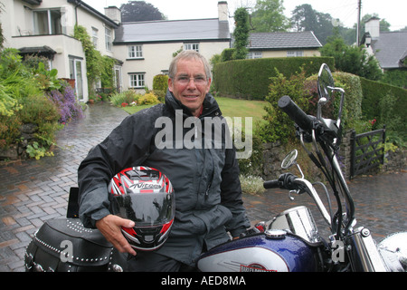 65 Jahre alter Mann mit Harley Davidson Motorrad außerhalb seines Hauses Leute Lifestyle Wales Stockfoto