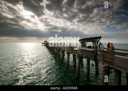 Die alte hölzerne Pier am Strand von Naples mit dramatischen stürmischen Himmel und Sonnenstrahlen über dem Meer Stockfoto