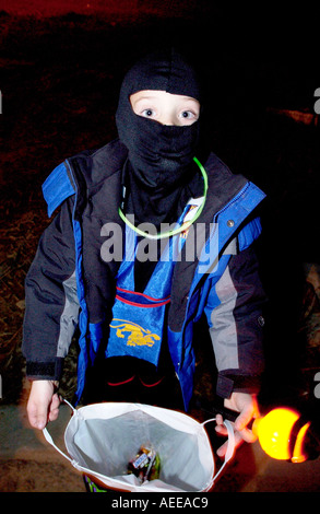 Kind im Ninja-Kostüm, die Öffnung der Tasche für Leckereien während Sie Süßes oder Saures zu Halloween Stockfoto