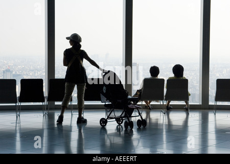 Silhouette einer Frau mit Kinderwagen und zwei Frauen sitzen auf Stühlen und ein Panoramafenster mit Blick Stockfoto