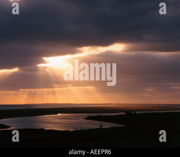 Dieses Foto zeigt ein ruhiges Meer mit der Sonne dunkle Wolken durchbrechen Stockfoto