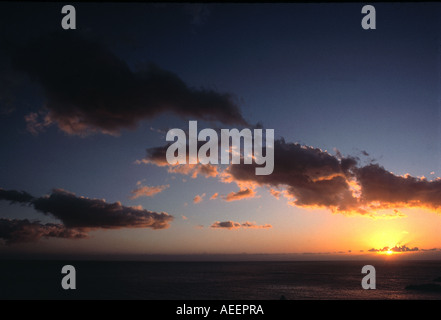 SONNENUNTERGANG AUF EINE SEENLANDSCHAFT MIT DUNKLEN WOLKEN VOR BLAUEM HIMMEL Stockfoto