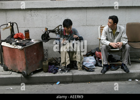 Ein Schuh-Werkstatt bei der Arbeit mit seiner Werkstatt auf der Straße in der Altstadt von Shanghai Stockfoto