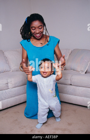 Hübsche Mutter stolz zufrieden glücklich progressive Fortschritt Fortschritt hilft niedlichen Lachen glücklich Baby Kleinkind 9 bis 12 Monate alte Spaziergang nach Hause Teppich POV Herr Stockfoto