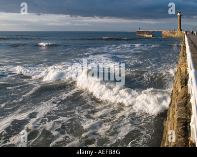 Whitby West Pier an einem Sommerabend mit rauer See Stockfoto