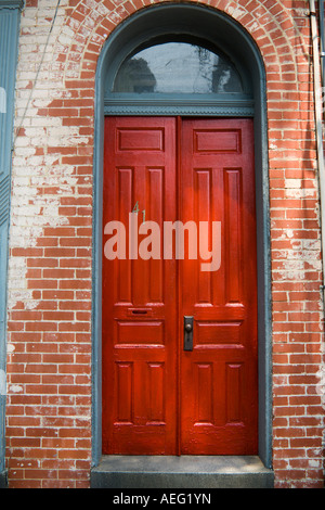 Große rote Doppeltüren mit Halbkreis Riegel in geflickten Backsteingebäude Stockfoto