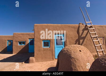 Ein Brotbackofen und Leiter vor Adobe Wohnungen in Taos Pueblo, Taos, New Mexico Stockfoto