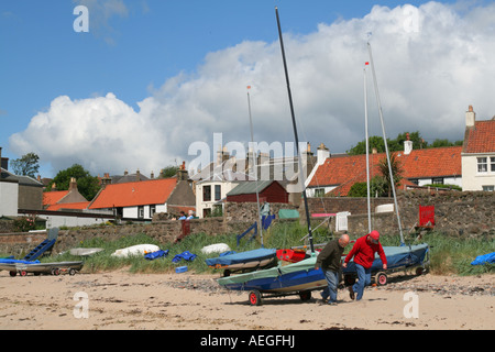 Zwei Männer ziehen ein Boot am Strand entlang in Lower Largo, Fife, Schottland. Stockfoto