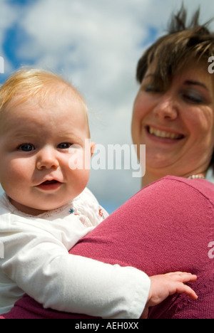 Vertikale hautnah Porträt der stolze junge Mutter mit ihrer Tochter lächelnd an einem sonnigen Sommertag. Stockfoto