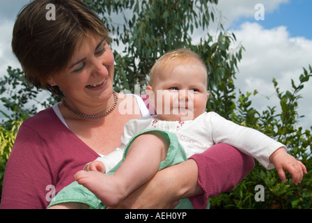 Horizontal nahe Porträt der stolze junge Mutter mit ihrer Tochter lächelnd an einem sonnigen Sommertag. Stockfoto