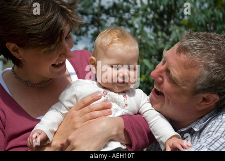 Horizontale Nahaufnahme Portrait einer jungen Familie (Mama, Papa und sechs Monate alten Erstgeborenen Tochter) im Garten. Stockfoto