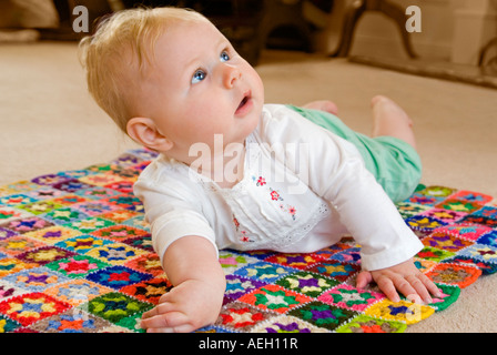 Horizontale nahe Porträt eines sechs Monate alten kaukasischen Mädchens selbst anheben, während auf dem Boden Stockfoto