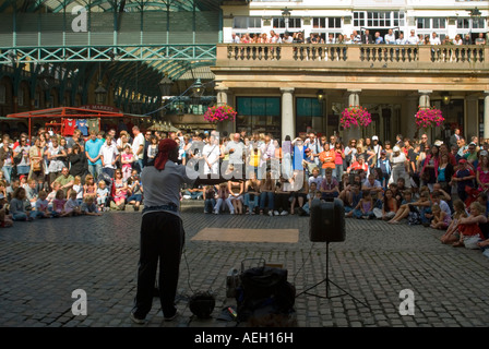Horizontale Nahaufnahme von einem Straßenkünstler unterhalten die Massen an einem hellen sonnigen Abend auf der Piazza in Covent Garden Stockfoto