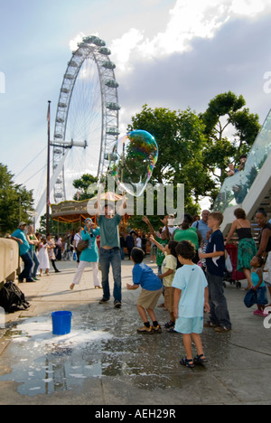 Vertikale Ansicht der Straßenkünstler riesige Luftblasen unterhaltsam eine Schar von Kindern auf der Southbank in London zu schaffen. Stockfoto