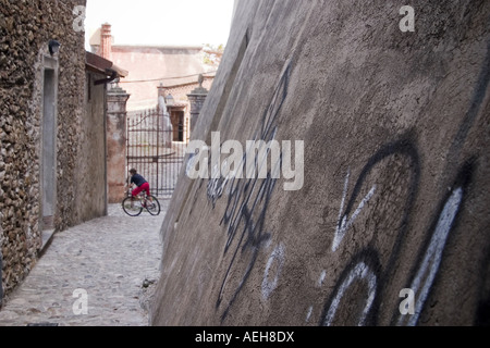 Ein Radfahrer auf dem Weg durch das malerische und ruhige Kopfsteinpflaster gesteinigt Backstreet Gassen in der Stadt von Loano Ligurien Italien Stockfoto