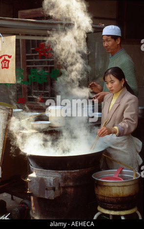 Muslimische paar Kochen mit einem großen Wok in den Gassen von muslimischen Viertel, Xian Shaanxi, China Stockfoto