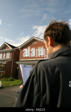 Ein junger Mann als Landvermesser arbeiten macht eine Umfrage einer Neubau Immobilie vor einem Hausverkauf. Stockfoto