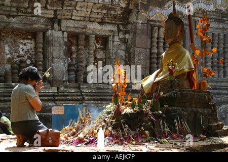 Junge buddhistische Frau beten vor einer Buddhastatue im Tempel Wat Phou, Wat Phou, Laos Stockfoto