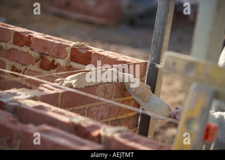 ARBEITER, DIE VERLEGUNG VON STEINEN MIT MÖRTEL AUF EINER BAUSTELLE IN GROßBRITANNIEN, EIN HAUS ZU BAUEN Stockfoto