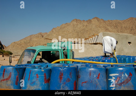 Eine ägyptische Beduinen native Nachfüllen Trinkwasser in Kunststoffbehälter in Wüste Sinai Ägypten Stockfoto