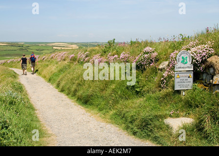 National Trust-Zeichen neben South West Coast Path Wanderer auf Hügel Wanderweg oberhalb Kirche Bucht in der Nähe von Mullion Stockfoto