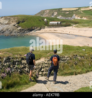 South West Coast Path Wanderer Pause der Church Cove Gunwalloe Cornwall einschließlich Kirche des Heiligen Winwaloe am Meer Strand zu bewundern, Großbritannien Stockfoto