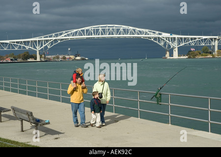 Familie Spaziergänge entlang der Promenade in Port Huron, Michigan mit der Blue Water International Bridge im Hintergrund Stockfoto