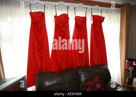 4 helle rote Bräute Mägde Kleider hängen von einem Fenster in ein Haus auf einer Hochzeit Tag morgen UK Stockfoto