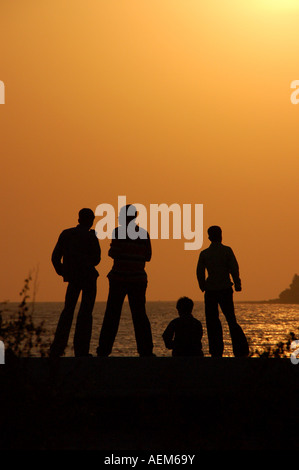 Vier Freunde am Deich bei Sonnenuntergang in Mumbai, Indien Stockfoto