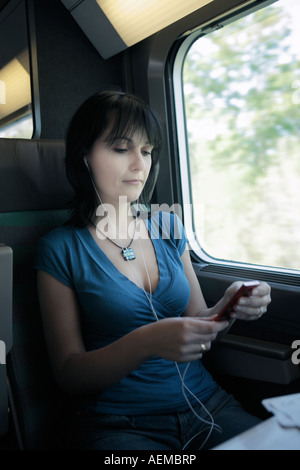 schöne junge Frau in einem Zug anhören von Musik auf einen MP3-Player Ipod Typ Stockfoto