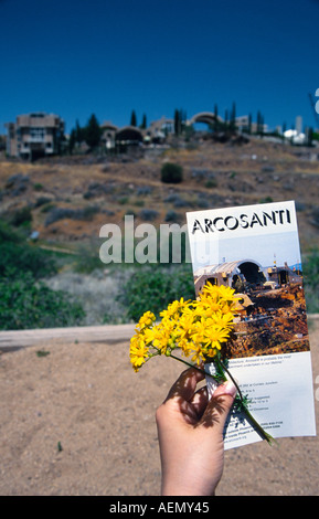 Hand halten eine Flyer und gelb Blume in Arcosanti experimentelle Stadt in der Wüste Mayer Arizona Usa Stockfoto