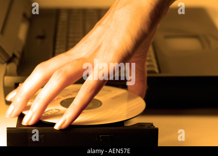 Frau eine CD aus dem CD-Rom-Laufwerk eines Laptop-Computers entfernen Stockfoto