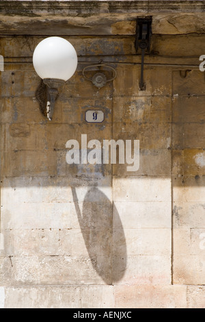 Globe-Lampe an Wand in engen Straße in der alten Stadt von Ceglie Messapica, Apulien, Süditalien. Stockfoto