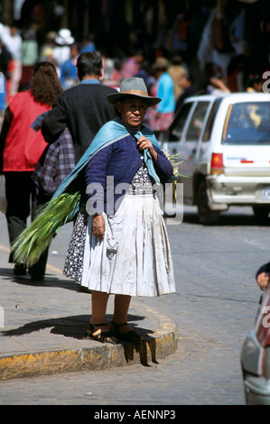Peruanischen Dame Tragetasche von Gemüse über die Schulter, stehend auf einem Bürgersteig, Cusco, Peru Stockfoto