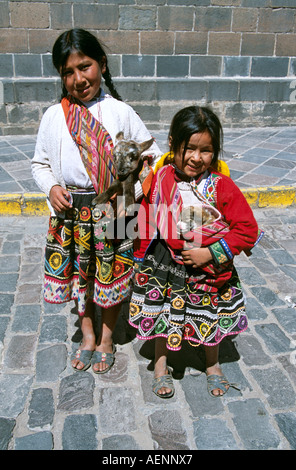 Zwei junge Mädchen tragen bunte Kleidung hält ein Lamm und ein Hund in ihren Armen, Cusco, Peru Stockfoto
