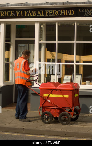 Briefträger mit Trolley Post tun seine Runde Zustellung von Briefen in Lampeter Ceredigion West wales Stockfoto