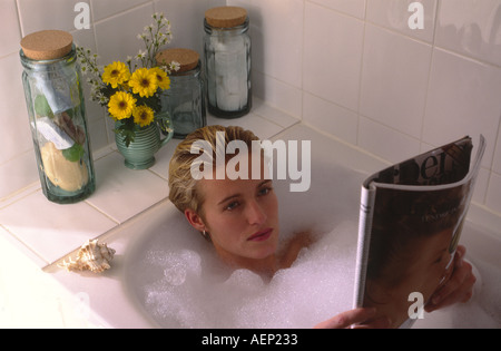 Junge, blonde Frau im Bad mit einem Magazin liegen. Stockfoto
