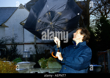 Mann mit Schirm weht in-und auswendig an windigen Tag Stockfoto